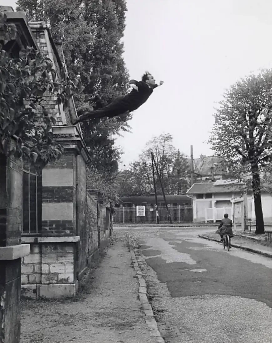 Vintage black and white photo of a man taking a swan dive off a garage. It looks like he is about to be splattered on the pavement below (he wasn't).
